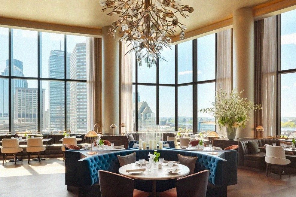 Tufted blue banquette and chandelier at the Raffles Boston sky restaurant